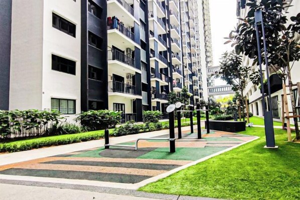 A multi-story residential building with balconies, a green lawn, and a pedestrian pathway. - Fluffy Stay at Huni Setia Alam by HCK (Shah Alam)