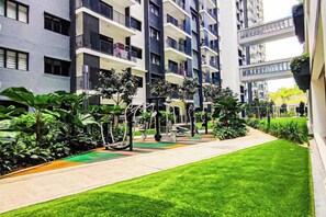 A residential building with multiple balconies, a green lawn, and outdoor seating areas. - Fluffy Stay at Huni Setia Alam by HCK (Shah Alam)