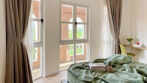 A bedroom with a bed, a window, curtains, and a small shelf with items. - Express by M Village Pham Ngu Lao, a brand of Modern Village Lifestyle (Ho Chi Minh City)