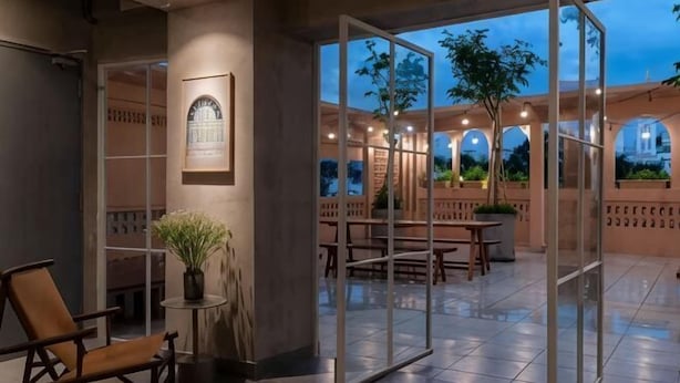 A hotel lobby with a glass partition, seating area, and a framed picture on the wall. - Express by M Village Pham Ngu Lao, a brand of Modern Village Lifestyle (Ho Chi Minh City)