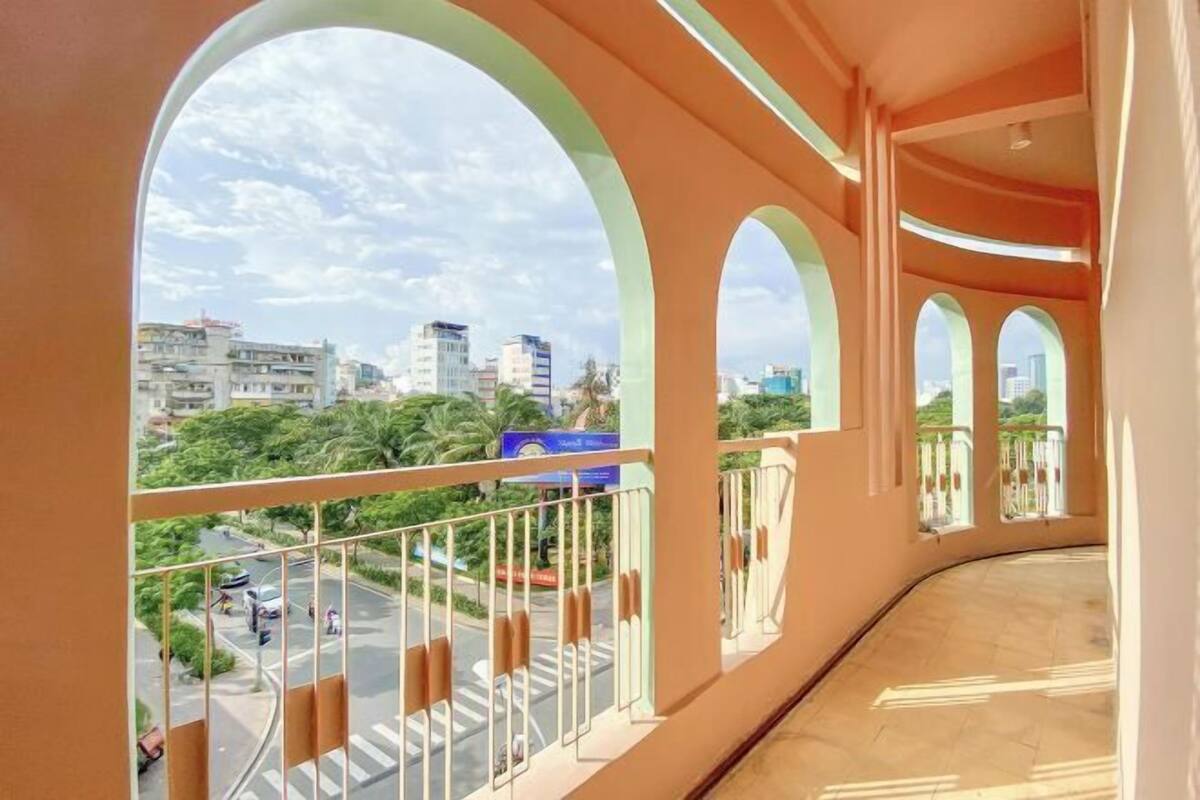 Un balcon doté d’une balustrade incurvée, offrant une vue sur un paysage urbain avec des bâtiments et de la verdure.