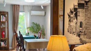 A dining area with a table, chairs, a lamp, and a bookshelf. - TangWu (Ito)