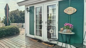 A wooden deck with a metal chair and a small table with a potted plant. - TangWu (Ito)