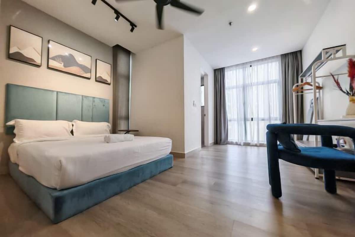 A modern hotel room with a bed, a chair, and a view of the outdoors.