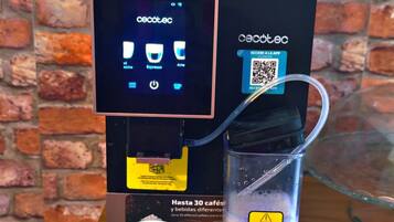 A coffee machine with a digital display, a cup of coffee, and a stack of newspapers.