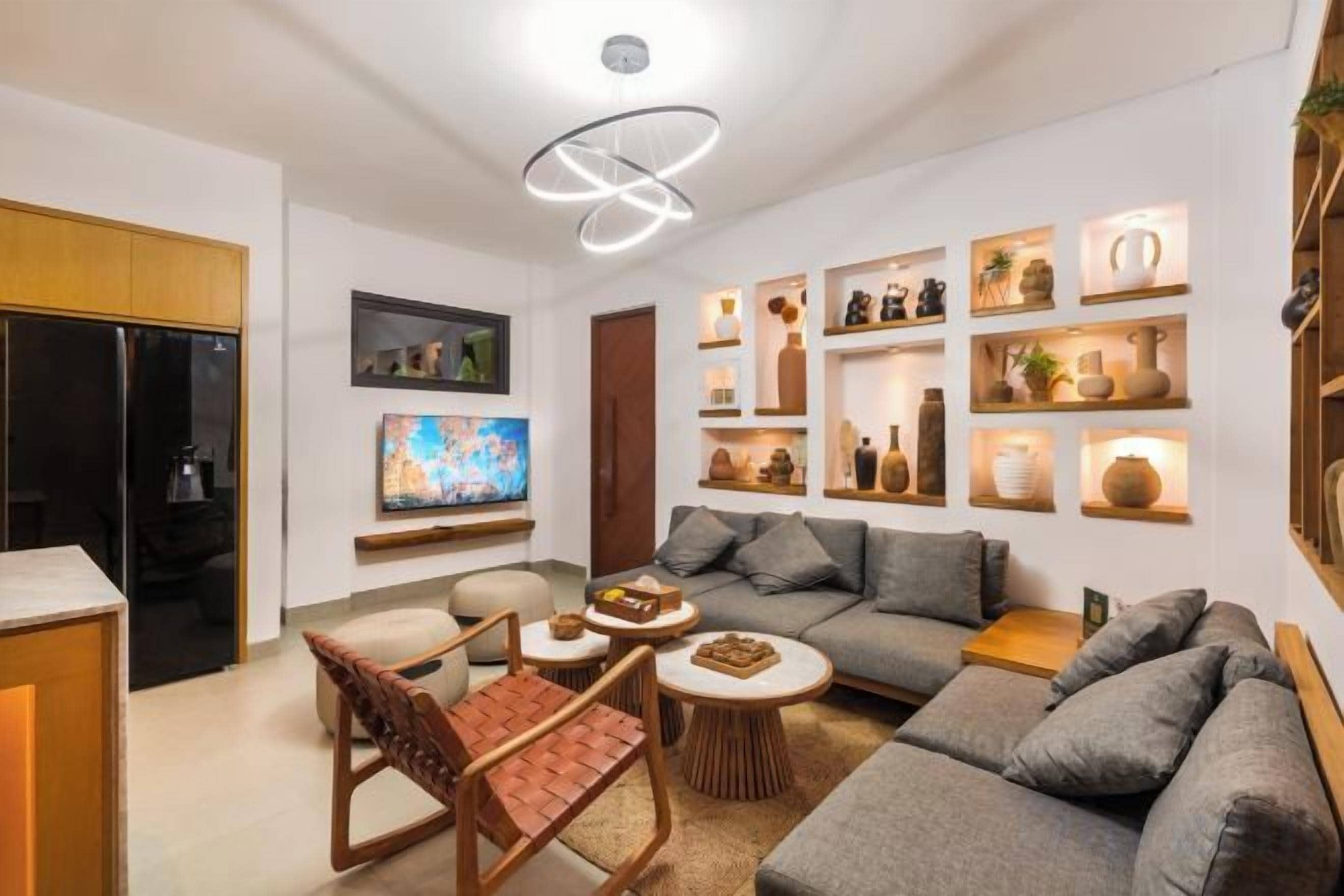 A modern living room with a sectional sofa, a coffee table, a TV, and decorative shelves.