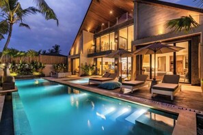 A modern house with a swimming pool, lounge chairs, and umbrellas. - Villa Moana by BaliSuperHost (Bali)