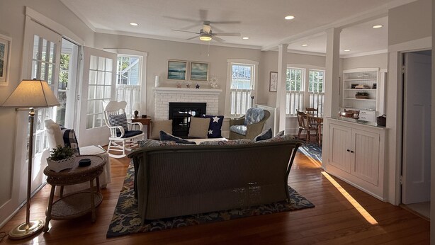A spacious living room with a fireplace, a ceiling fan, and a dining area with wooden furniture. - 418 E. Third In Lakeside (Lakeside)