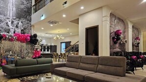 A spacious living area with a sofa, a coffee table, and a decorative wall with a waterfall mural. - Villa Homescape, Mont Kiara (Kuala Lumpur)