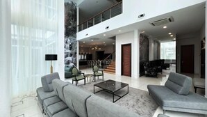A spacious lobby with grey sofas, a marble coffee table, and a staircase leading to an upper level. - Villa Homescape, Mont Kiara (Kuala Lumpur)