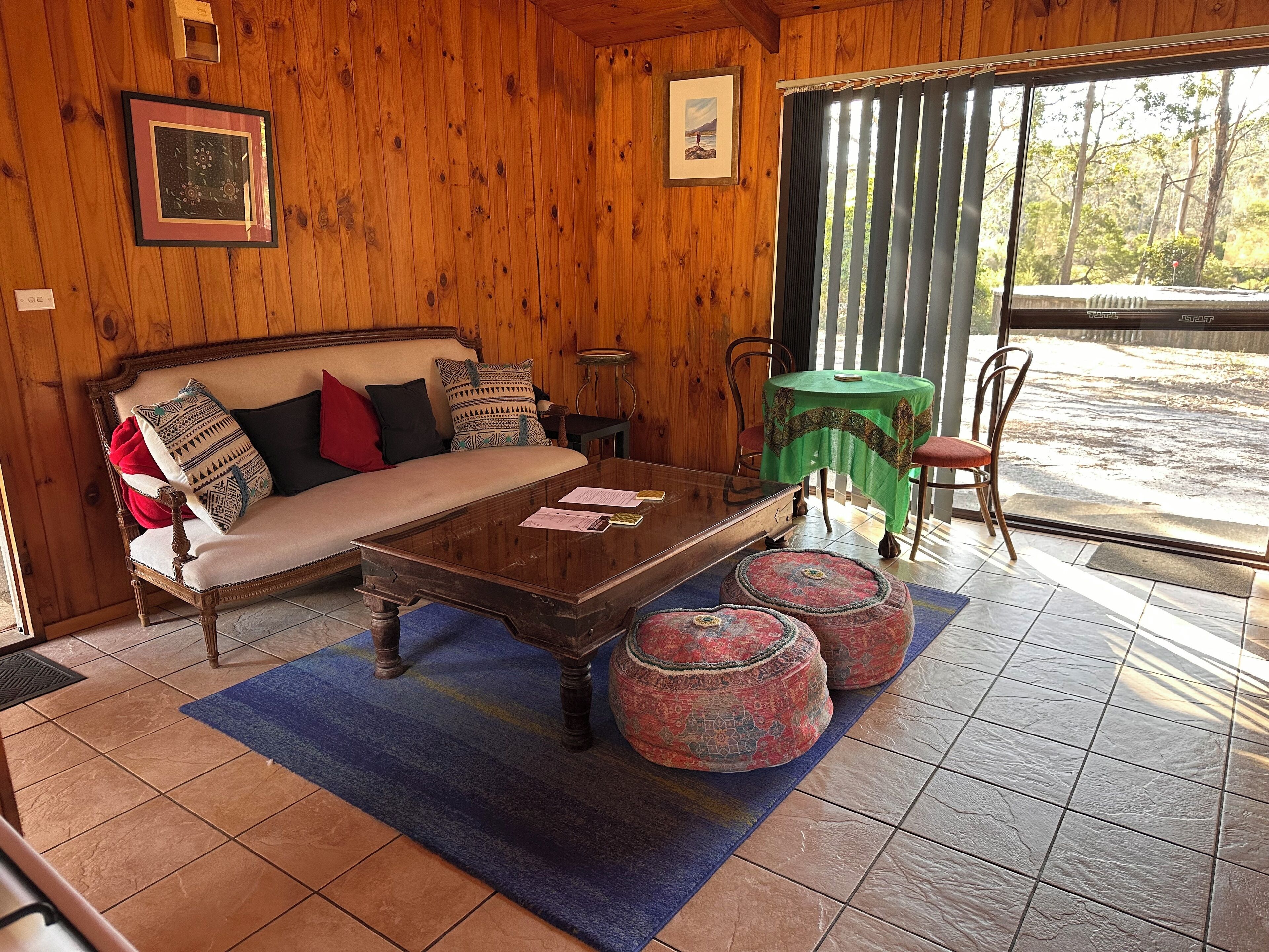 A wooden interior with a sofa, a coffee table, and a view through a window.