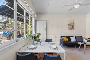 A dining area with a table set for four, a sofa, and a ceiling fan.