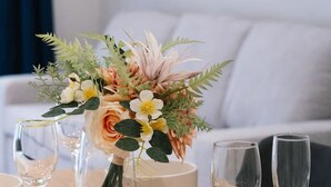 A dining table with a floral centerpiece, several wine glasses, and plates.