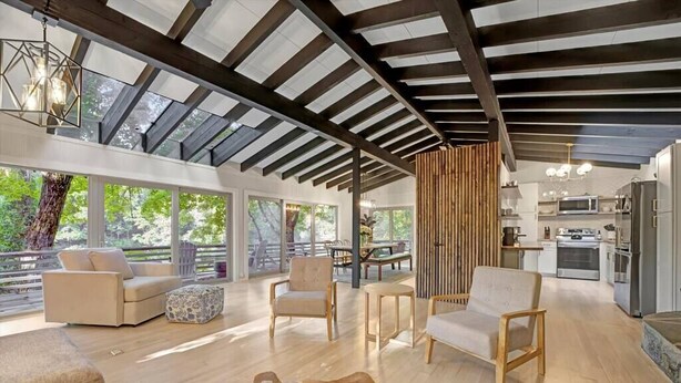 Amplia sala de estar con techo alto, ventanas grandes y una cocina moderna.