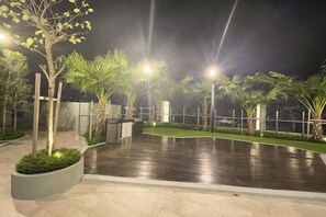 An outdoor area with a paved surface, palm trees, and a fence. - Alfa Bangsar by The Homez (Kuala Lumpur)