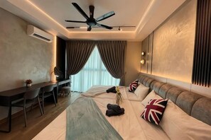 Una camera d'hotel con un letto, una scrivania, una sedia, una ventola a soffitto e una finestra con tende.