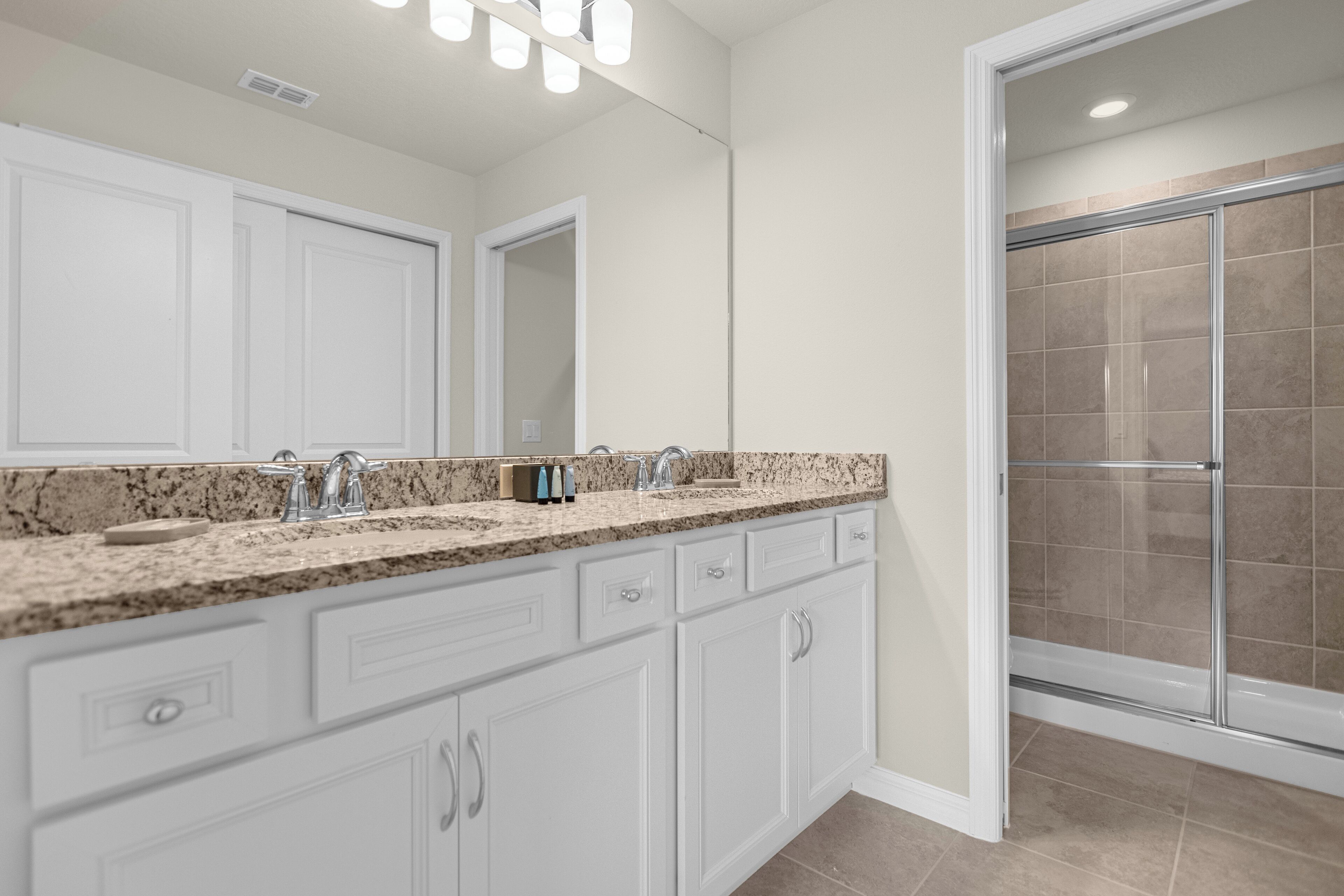 A modern bathroom with a large vanity, double sinks, and a glass shower enclosure.