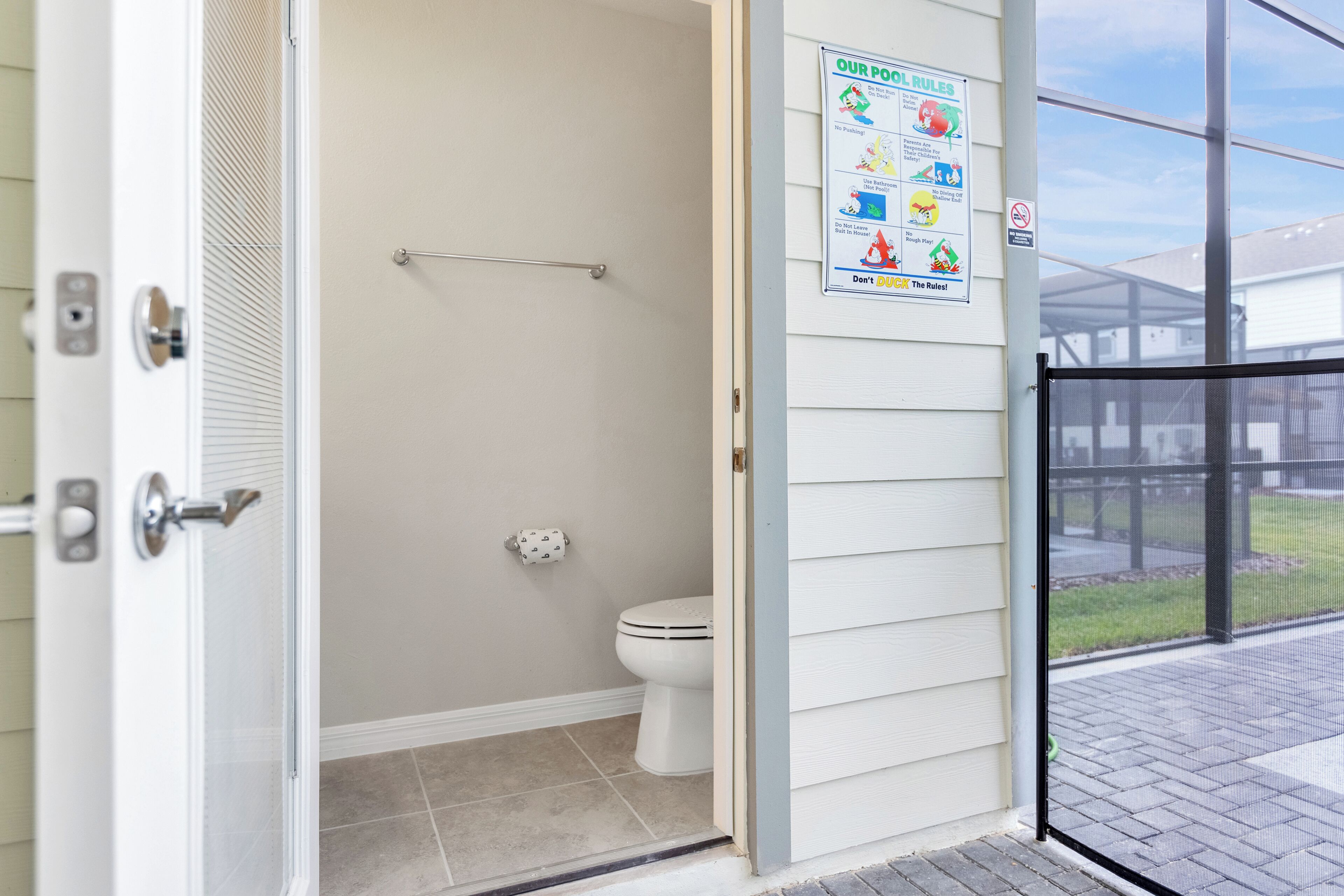 A bathroom with a toilet, a towel rack, and a poster with safety rules.