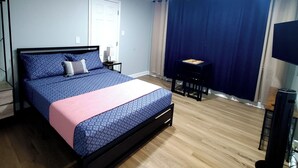 Una camera da letto con un letto, comodini, una scrivania, una sedia, una televisione e un termosifone.