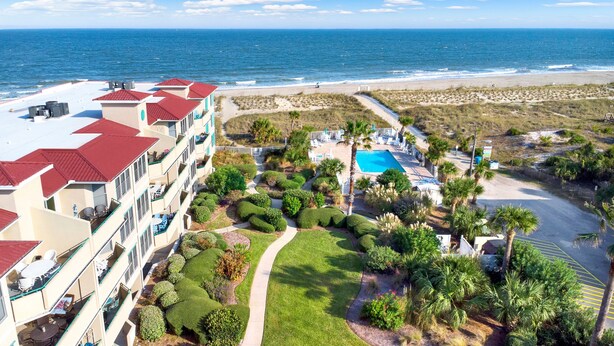 Un resort con piscina, vista a la playa y un jardín bien cuidado.