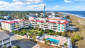 A beachfront hotel with multiple balconies, a swimming pool, and a view of the ocean. - Your Tranquil Tybee Retreat | Heated Pool Access (Tybee Island)