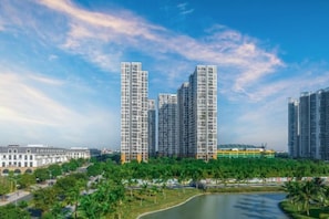 Un ensemble immobilier composé d’immeubles de grande hauteur abritant de nombreux appartements, d’un parc avec un étang et d’un ciel dégagé.