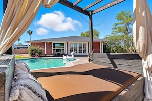 A pool area with a swan float, wooden deck, and a house in the background.