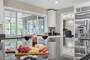 A modern kitchen with a glass countertop, stainless steel appliances, and a view of the outdoors.