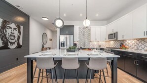 A modern kitchen with a central island, pendant lights, and a microwave.