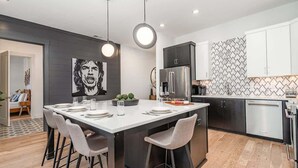 A modern kitchen with a central island, stainless steel appliances, and a dining area with chairs.