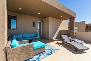 Un espace de vie extérieur comprenant un canapé, des fauteuils et un tapis à motifs.