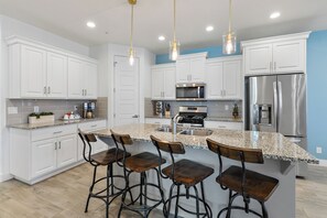 A modern kitchen with white cabinetry, a stainless steel refrigerator, a built-in microwave, and a granite countertop. - Grand Coral Estate Brand New Listing! (Washington)