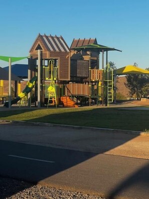 Une aire de jeux avec une structure en bois, des toboggans et un espace d’escalade.