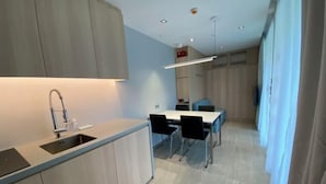 Una cocina moderna con un lavaplatos empotrado, una zona de comedor con mesa y sillas, y un piso de color claro.