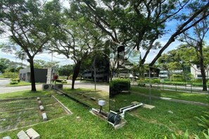 A park with trees, a paved walkway, and a small building. - Shipping Container Hotel at One-North (Singapore)