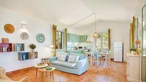 Ein geräumiger Wohnbereich mit einer Couch, einem Esstisch und einer Küche im Hintergrund.