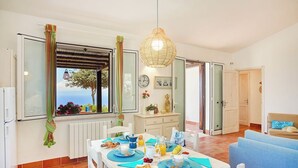 Ein Essbereich mit einem für das Frühstück gedeckten Tisch, Meerblick durch ein Fenster und ein modernes Interieur.