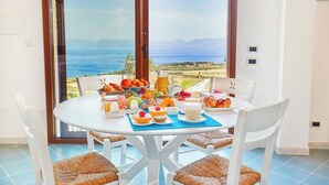 A dining table set with breakfast items and a scenic ocean view. - Brezza del Vento, Scopello area, Sicily (Scopello)