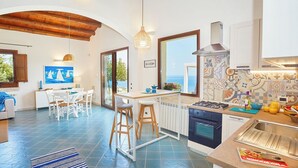 A modern kitchen with a gas stove, oven, and a view of the sea through large windows. - Brezza del Vento, Scopello area, Sicily (Scopello)