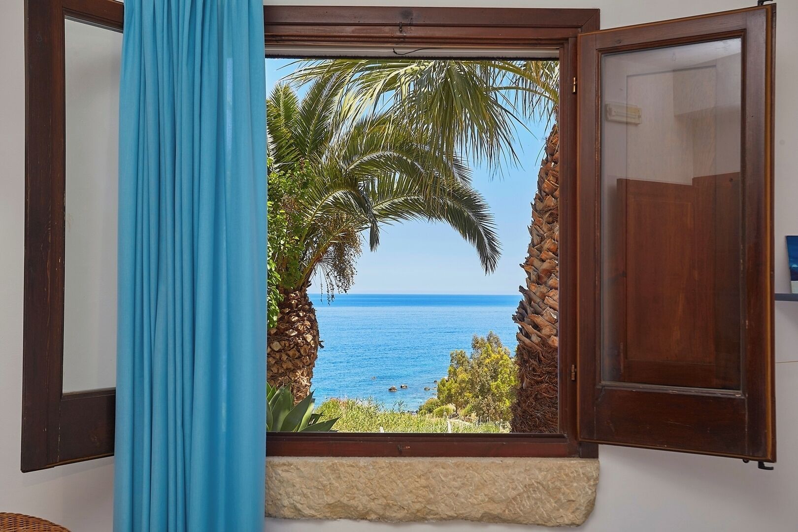 Ein Zimmer mit Meerblick, eine Holztür und ein blauer Vorhang.