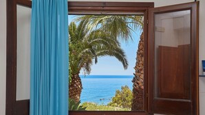 Una habitación con vista al mar, una puerta de madera y una cortina azul.
