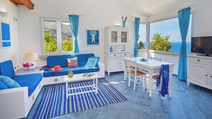 A bright room with a blue sofa, white cabinets, and a dining table.