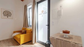 A modern room with a yellow sofa, a small table with a cake, and a sliding glass door with a sign.