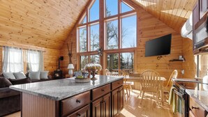 L’intérieur chaleureux de ce chalet est agrémenté de boiseries, d’une grande cuisine, d’une table à manger et d’un coin salon confortable.
