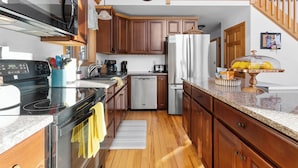 Une cuisine avec des meubles en bois, des appareils électroménagers en acier inoxydable et un escalier en bois.