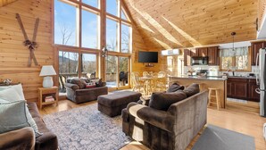 Un vaste espace de vie doté d’un haut plafond, de murs en bois et de grandes fenêtres.