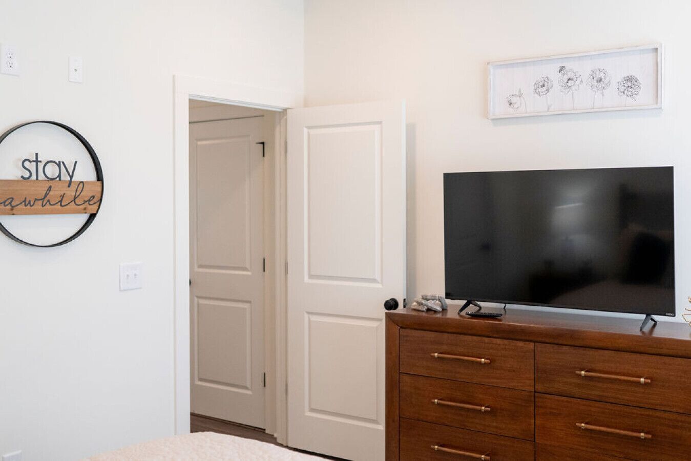 A bedroom with a bed, a dresser, a television, and a door.