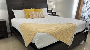 A neatly made bed with a dark headboard, white bedding, and a yellow throw blanket. - Villa Carmin 2 with Private Pool (Aguadilla)