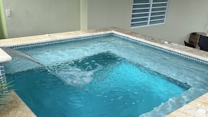 A rectangular indoor swimming pool with a tiled edge, a drain in the center, and a small plant beside it. - Villa Carmin 2 with Private Pool (Aguadilla)
