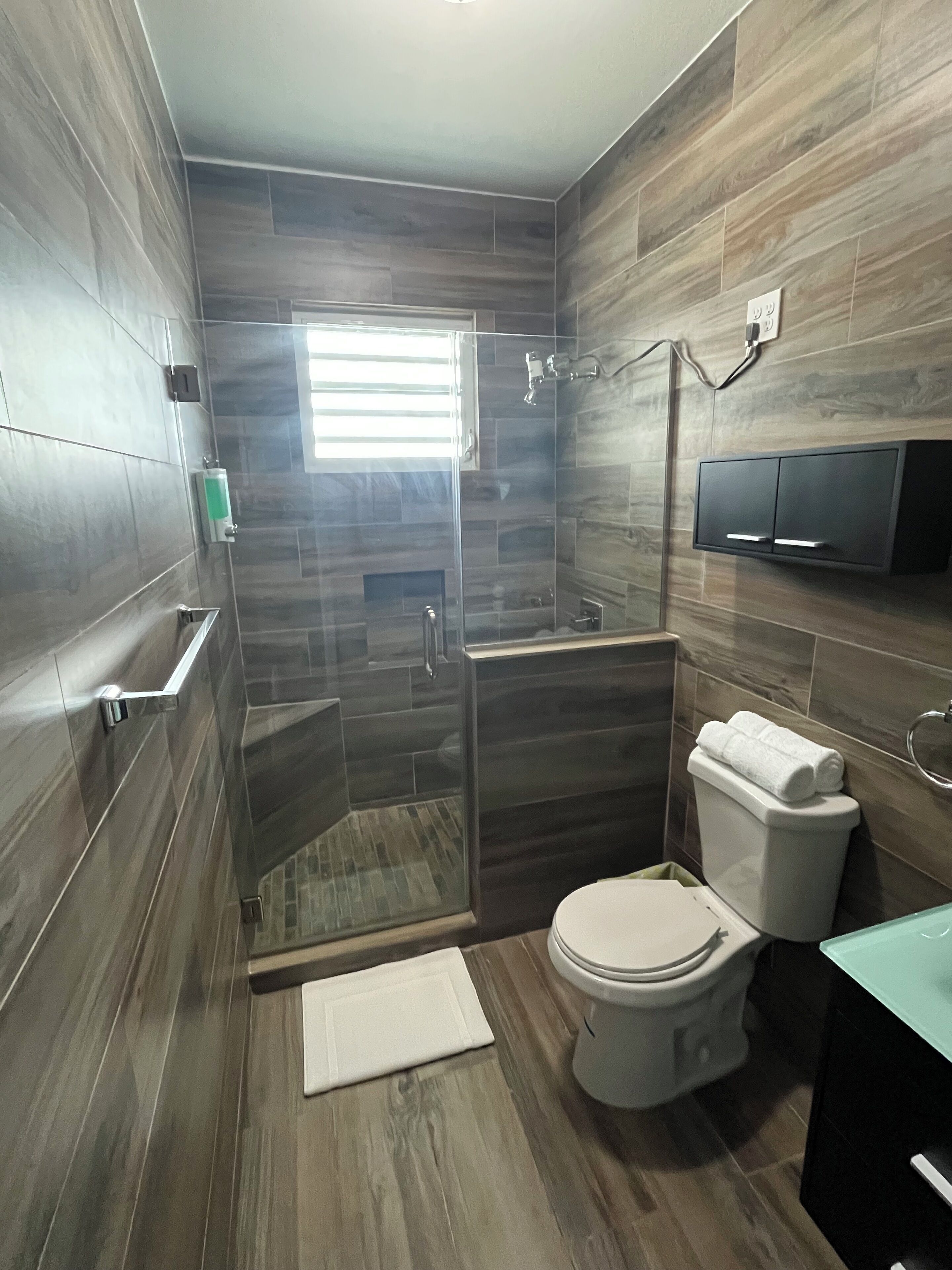 A modern bathroom with a shower, toilet, and a built-in TV.